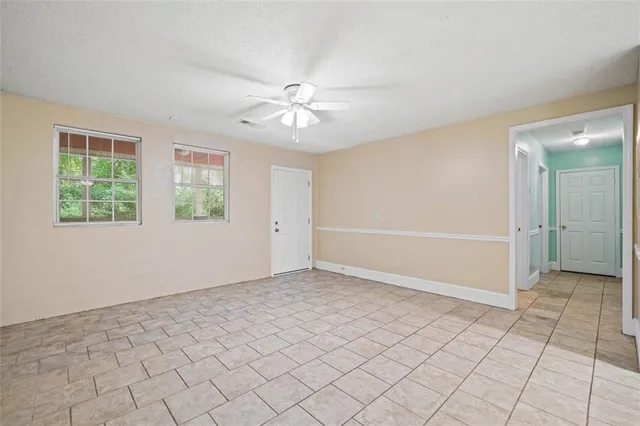 an empty room with windows and fan