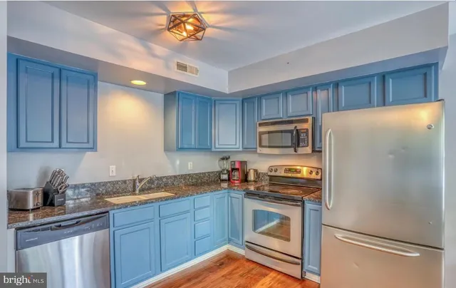 a kitchen with granite countertop stainless steel appliances a refrigerator a stove a sink cabinets and a refrigerator