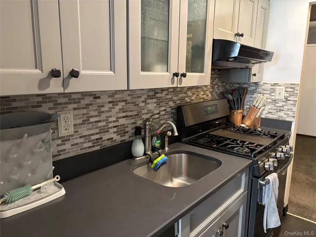 a kitchen with granite countertop a sink stove and cabinets