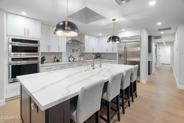 a kitchen with stainless steel appliances kitchen island granite countertop a table chairs sink and microwave