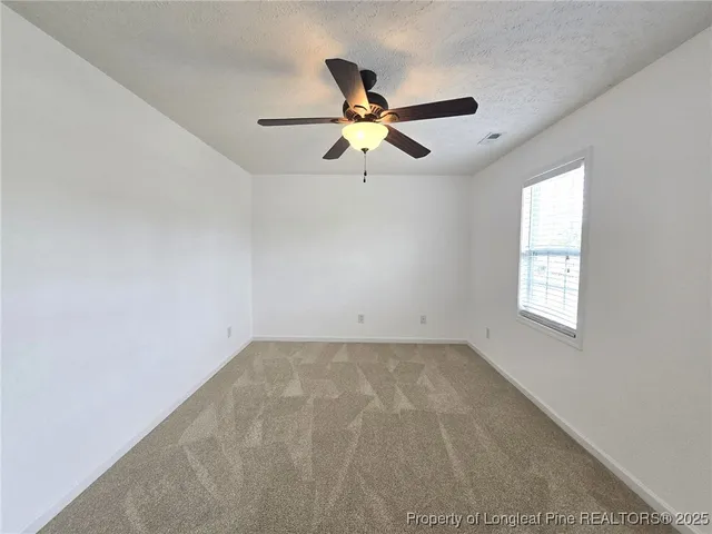 an empty room with windows and chandelier fan