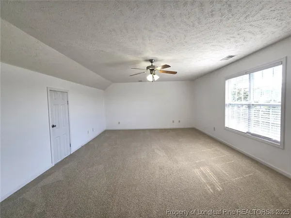 an empty room with chandelier fan and windows