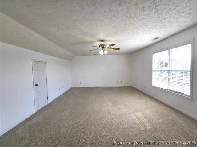 an empty room with chandelier fan and windows