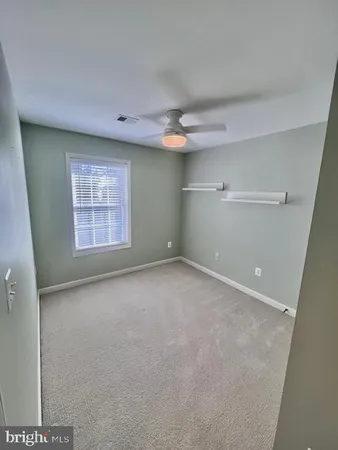 an empty room with a ceiling fan and window