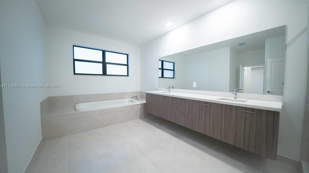 Sunset Lakes Miramar, FL 33029 - Photo 11 of 15 a bathroom with a bathtub a double vanity sink a vanity a mirror and a bathtub