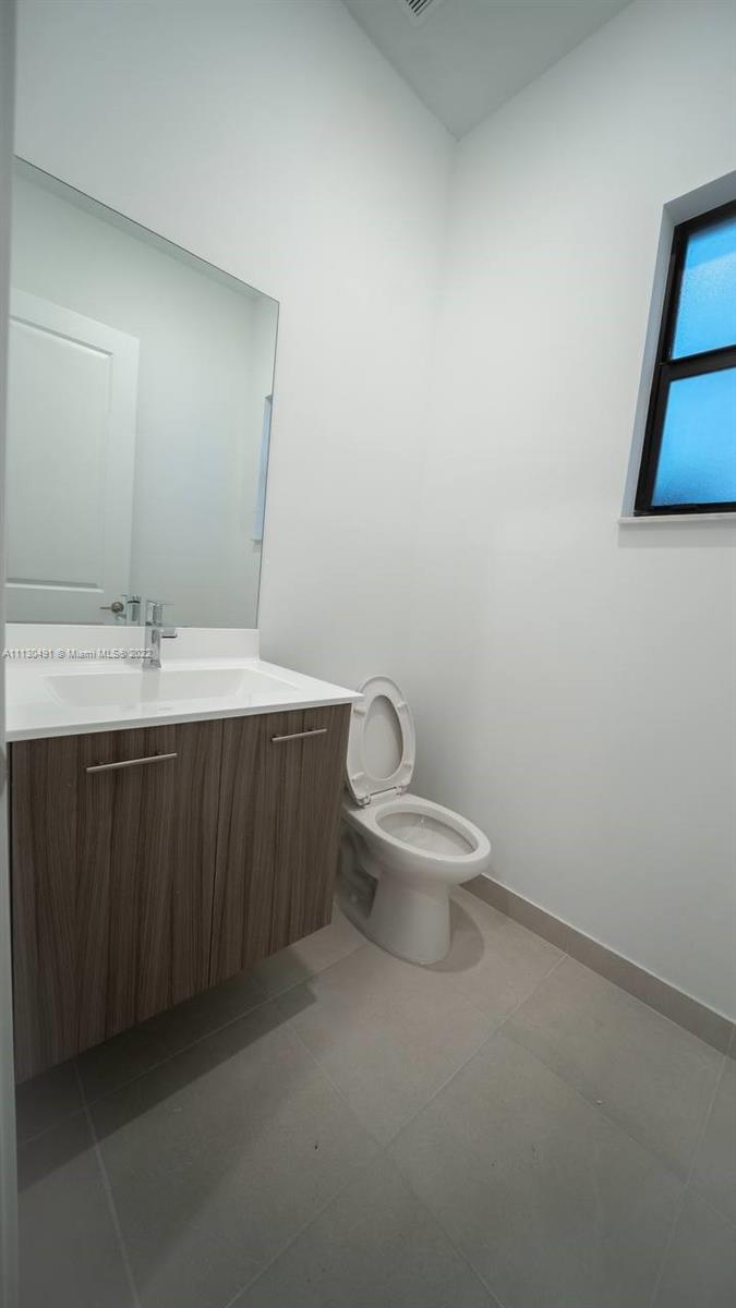 Sunset Lakes Miramar, FL 33029 - Photo 13 of 15 a bathroom with a toilet a sink and mirror