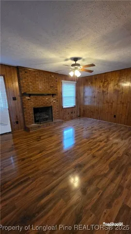 an empty room with wooden floor fireplace and windows