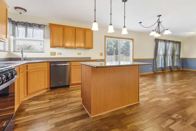 a large kitchen with stainless steel appliances granite countertop a sink a stove and a wooden floors