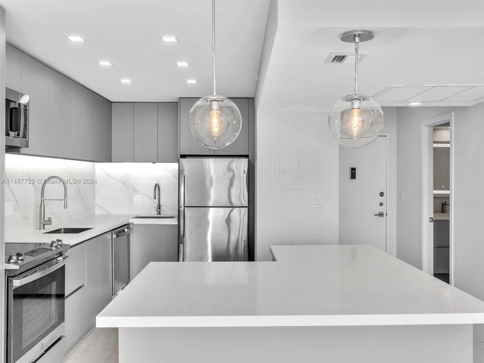 4101 Pine Tree Drive, Unit 621 620 Miami Beach, FL 33140 - Photo 12 of 73 a large white kitchen with kitchen island a sink stainless steel appliances and cabinets