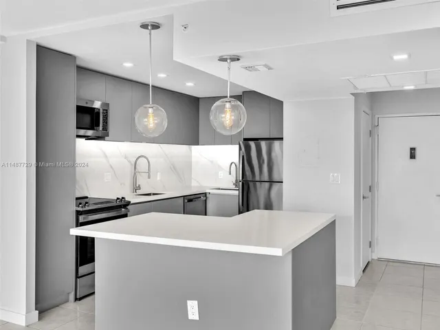 a large white kitchen with kitchen island a sink stainless steel appliances and cabinets