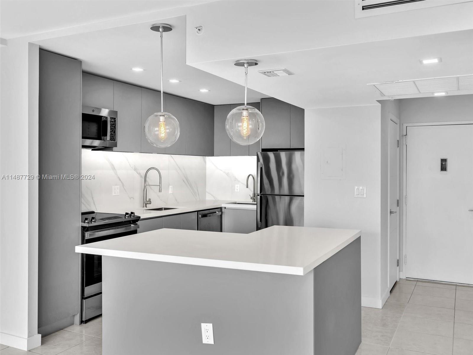 4101 Pine Tree Drive, Unit 621 620 Miami Beach, FL 33140 - Photo 10 of 73 a kitchen with stainless steel appliances a stove a microwave and white cabinets
