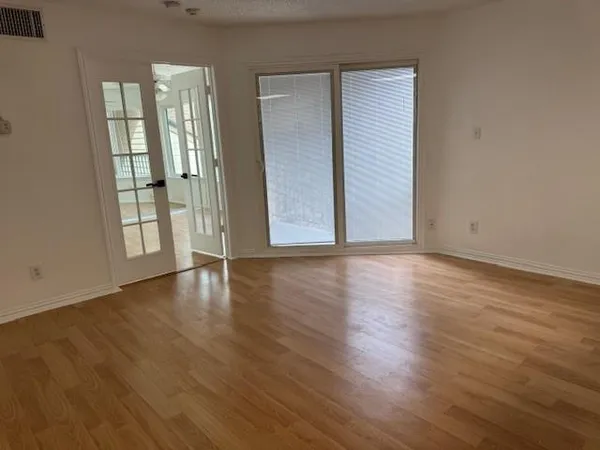 an empty room with wooden floor and windows