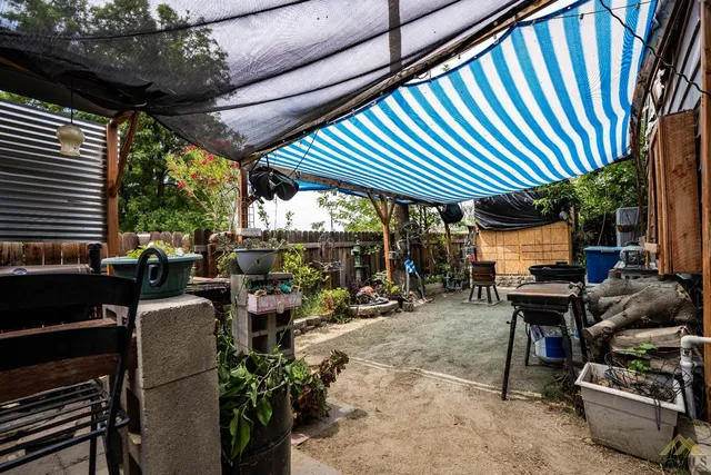 a view of a patio with table and chairs barbeque potted plants and large tree