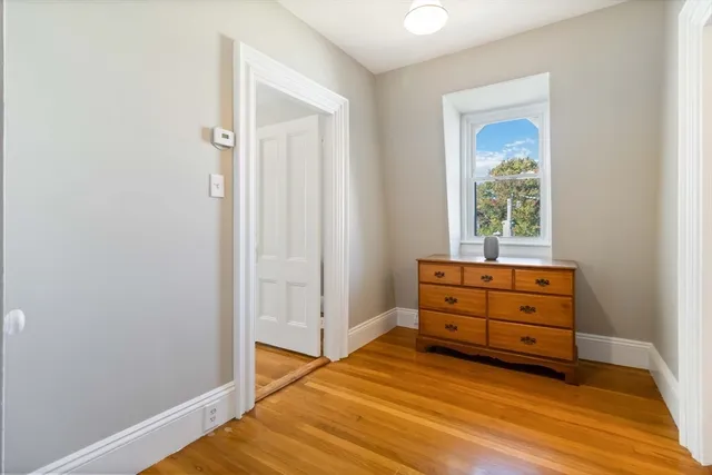 an empty room with wooden floor cabinet and window