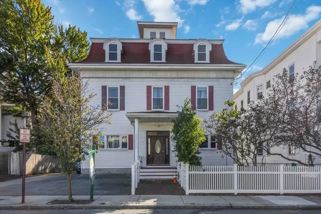 a front view of a house with a tree
