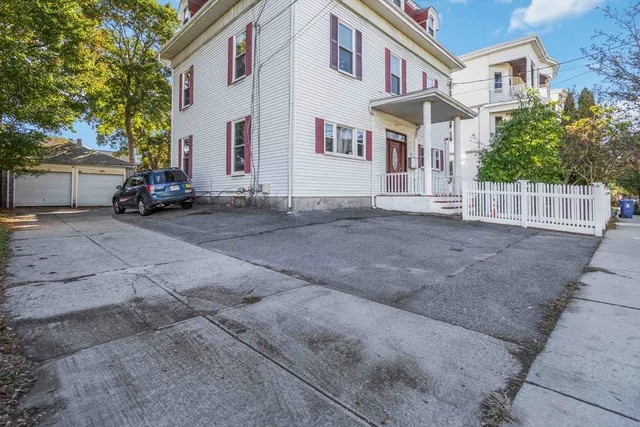 a view of a white house with a large space next to a road
