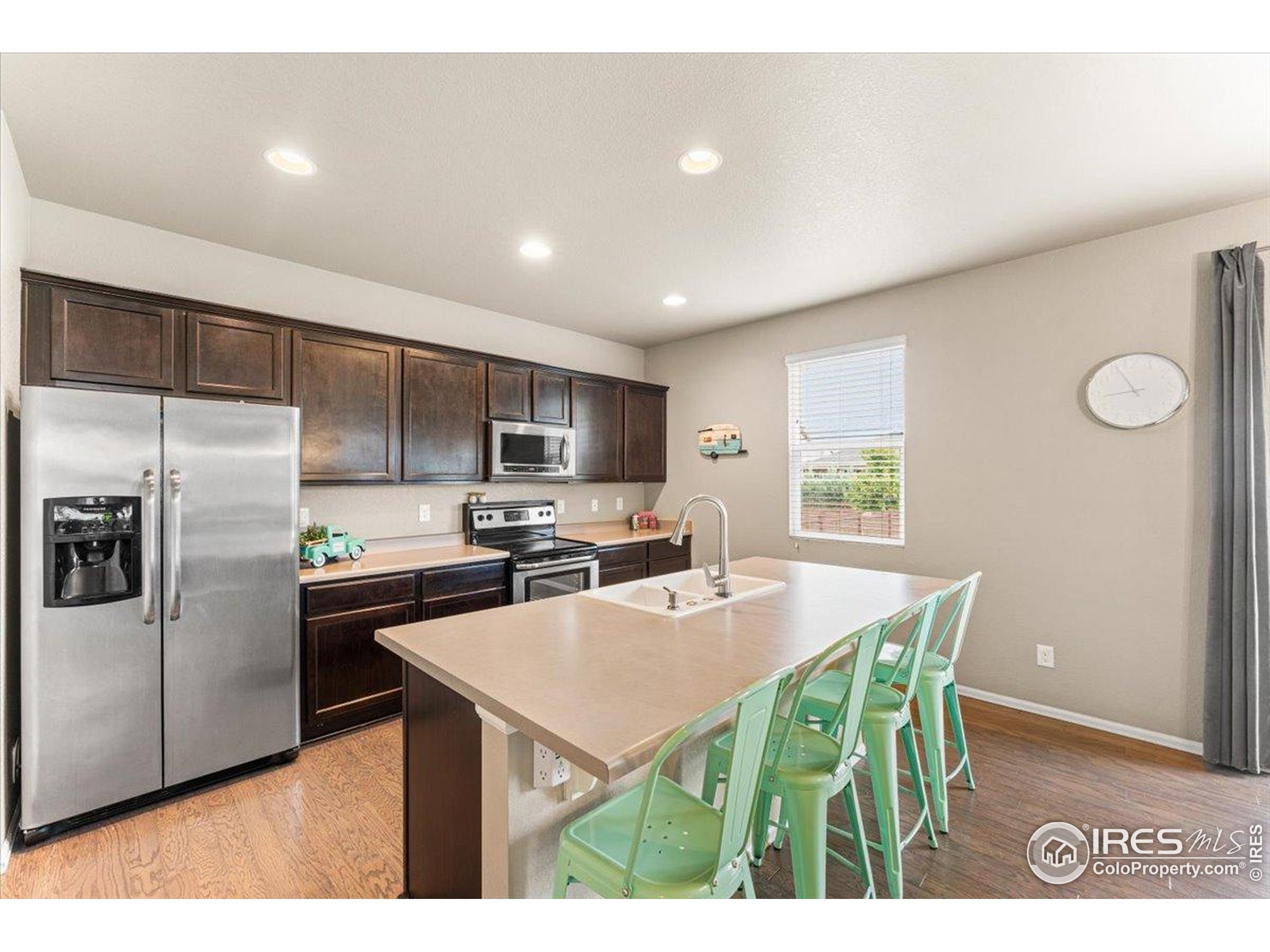 6747 Grainery Road Timnath, CO 80547 - Photo 3 of 42 a kitchen with stainless steel appliances a table chairs and a refrigerator