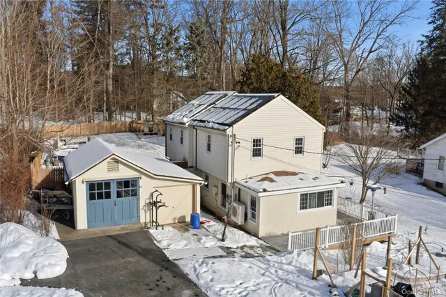 a view of a white house next to a yard with wooden fence and trees