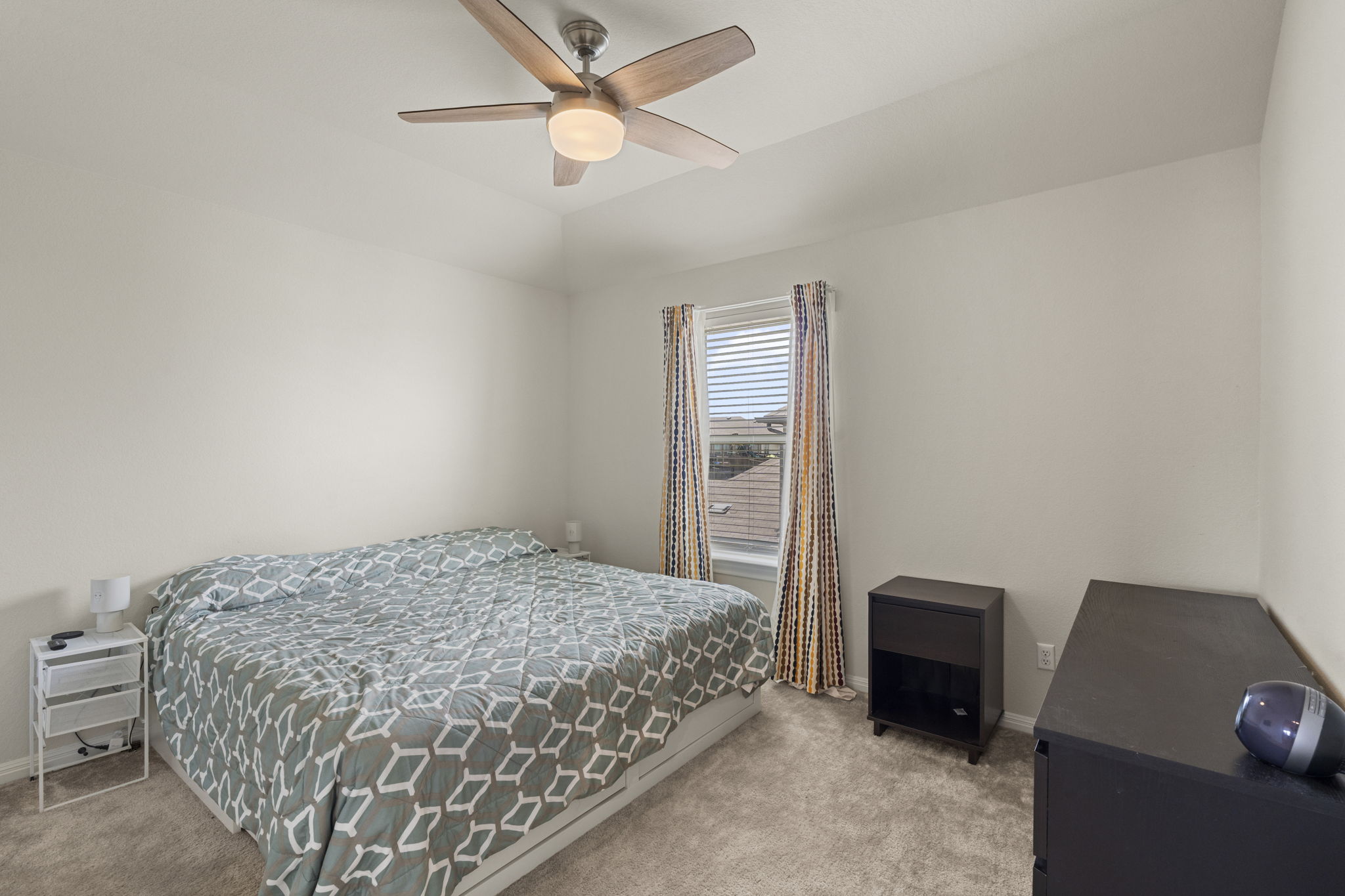 548 Purple Heart Drive Buda, TX 78610 - Photo 23 of 35 A well-lit sleeping sanctuary features a window with tasteful drapes and a central ceiling fan for optimal comfort.