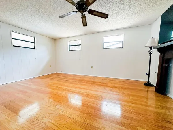 a view of empty room with wooden floor and fan