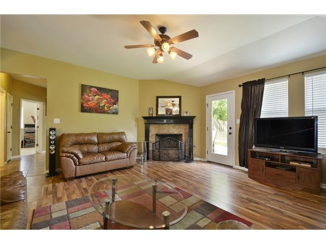11612 Timber Heights Drive Austin, TX 78754 - Photo 5 of 28 Staged previously. Natural light illuminates this cozy living space, featuring rich hardwood floors and a warm fireplace.