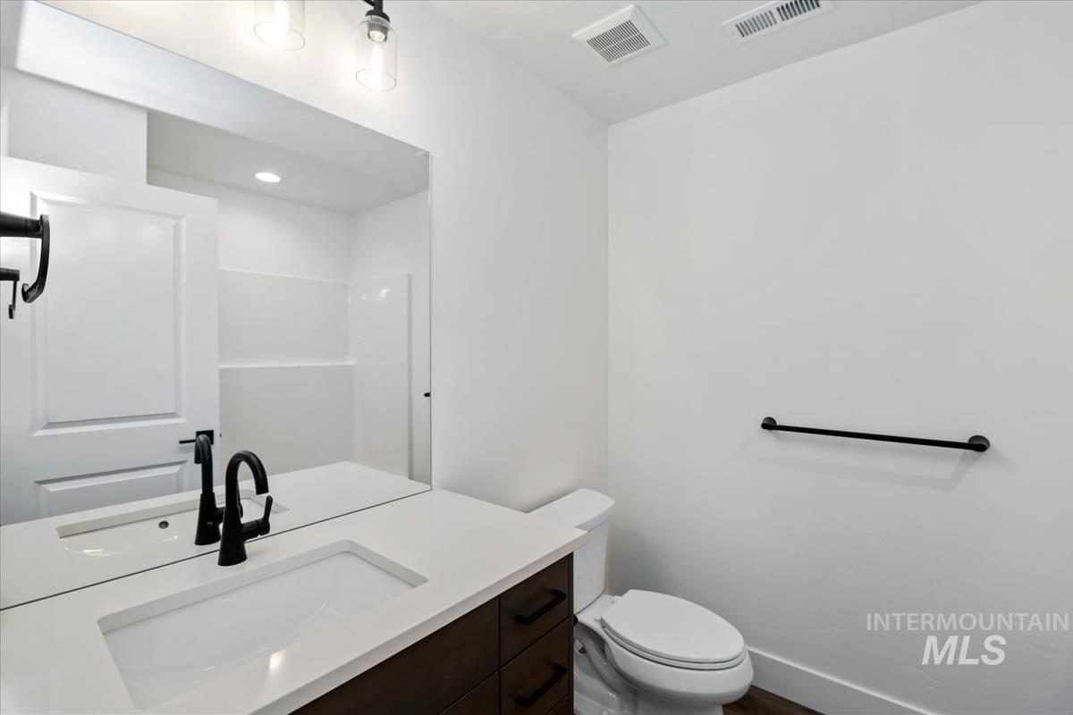 752 South Calhoun Lane Star, ID 83669 - Photo 26 of 45 Bathroom featuring a dark wood-finish vanity with an integrated white sink, a matte black faucet, and a large wall-mounted mirror