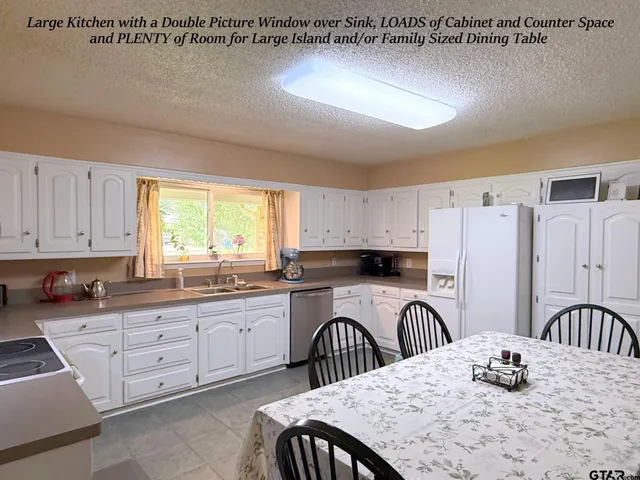 a kitchen with stainless steel appliances granite countertop a kitchen island a stove a sink a dining table and chairs