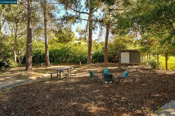 a view of swimming pool with outdoor seating and trees in the background