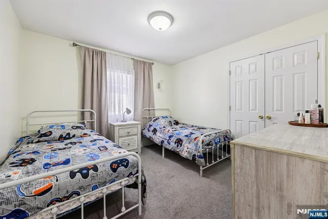 a bedroom with two beds and next to a window