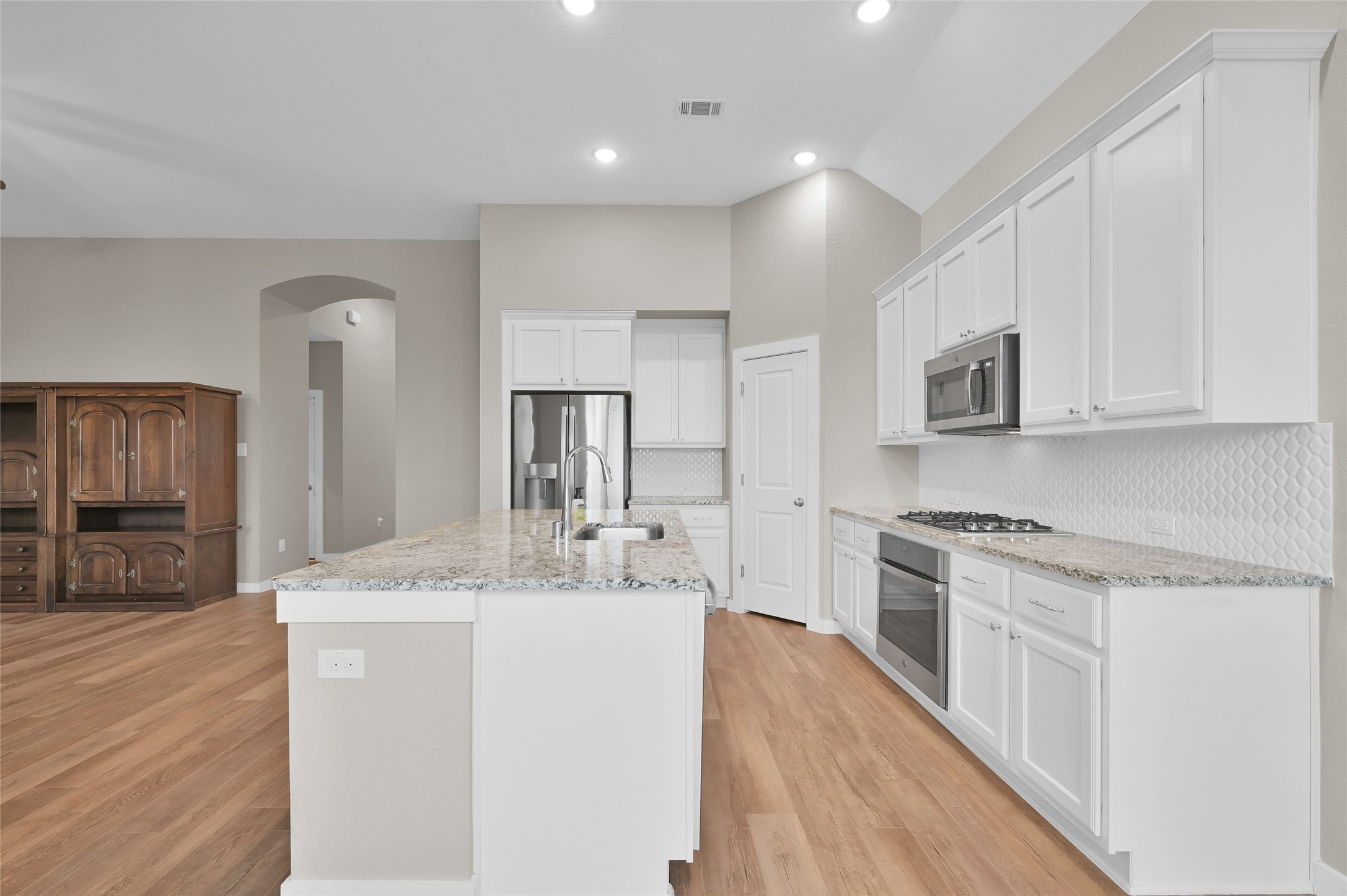 14960 Scarlet Branch Drive Conroe, TX 77302 - Photo 14 of 50 a large white kitchen with stainless steel appliances granite countertop a stove a sink a refrigerator and white cabinets with wooden floor