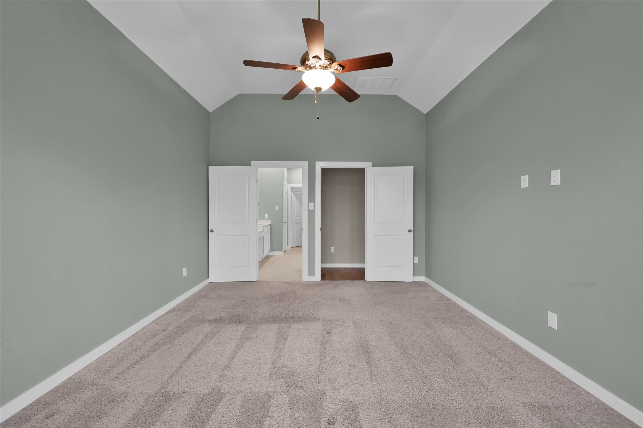 14960 Scarlet Branch Drive Conroe, TX 77302 - Photo 21 of 50 Spacious primary suite with vaulted ceilings, soft carpet, and a ceiling fan. Double doors lead into a bright en-suite bath with dual vanities.