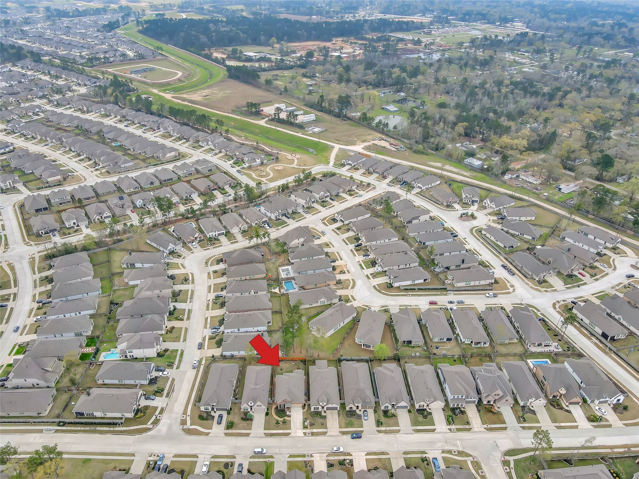 14960 Scarlet Branch Drive Conroe, TX 77302 - Photo 43 of 50 This aerial view highlights the home’s prime location (indicated by the red arrow), nestled among well-maintained properties with manicured lawns and attractive curb appeal.