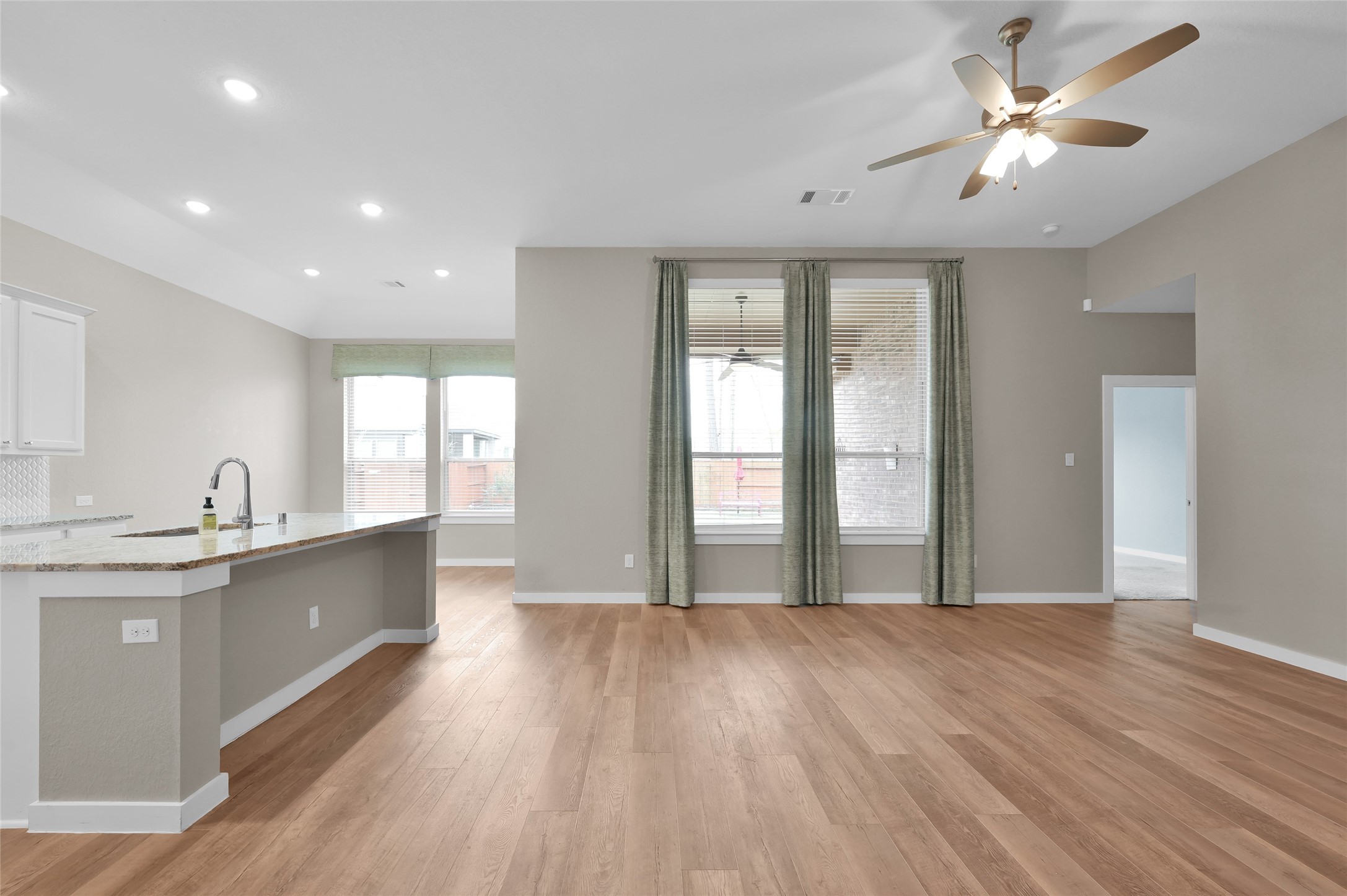 14960 Scarlet Branch Drive Conroe, TX 77302 - Photo 8 of 50 Open-concept layout with wood-look floors, a large island with granite counters, recessed lighting, and plenty of natural light from big windows.