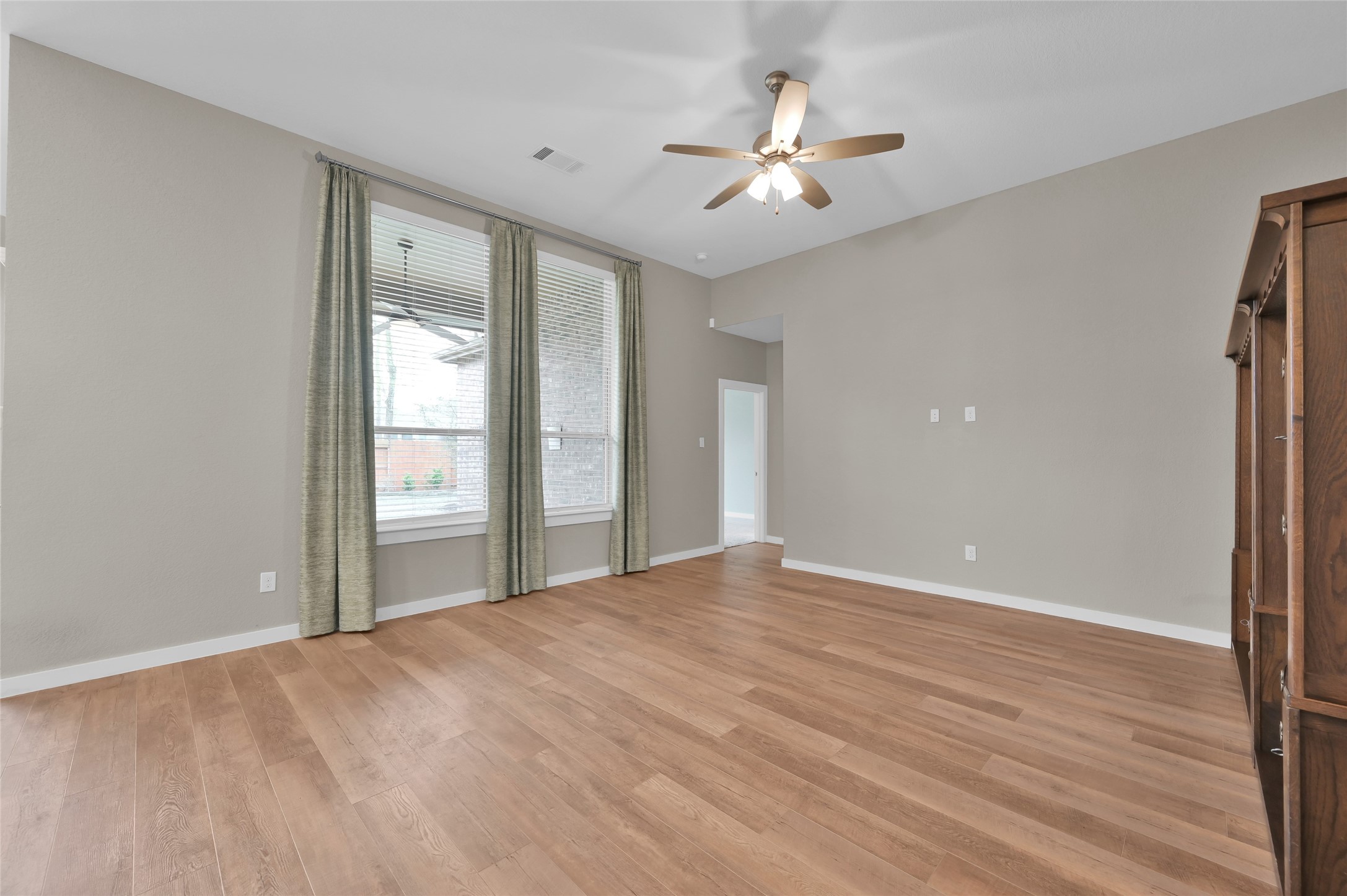 14960 Scarlet Branch Drive Conroe, TX 77302 - Photo 9 of 50 Spacious living area with wood-look flooring, granite island, and floor-to-ceiling windows that bring in tons of natural light.