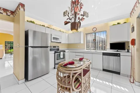 a kitchen with stainless steel appliances granite countertop a refrigerator a stove a sink dishwasher and a dining table with wooden floor