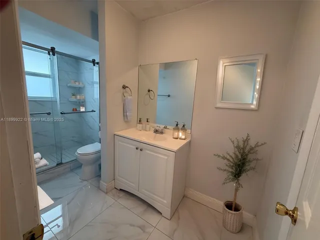 a bathroom with a granite countertop sink a toilet and shower