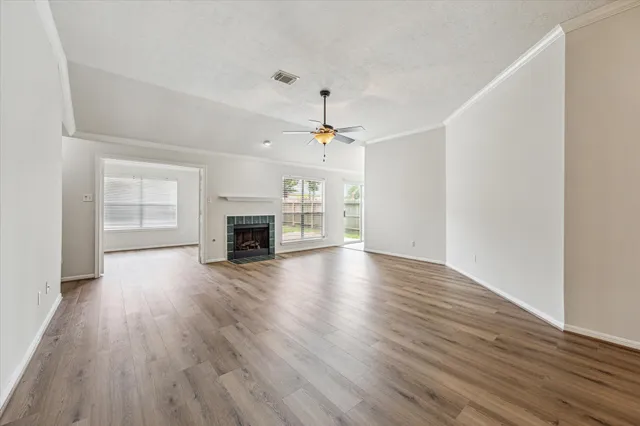 an empty room with wooden floor fireplace and windows