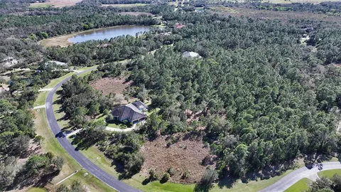 an aerial view of residential house with outdoor space and trees all around