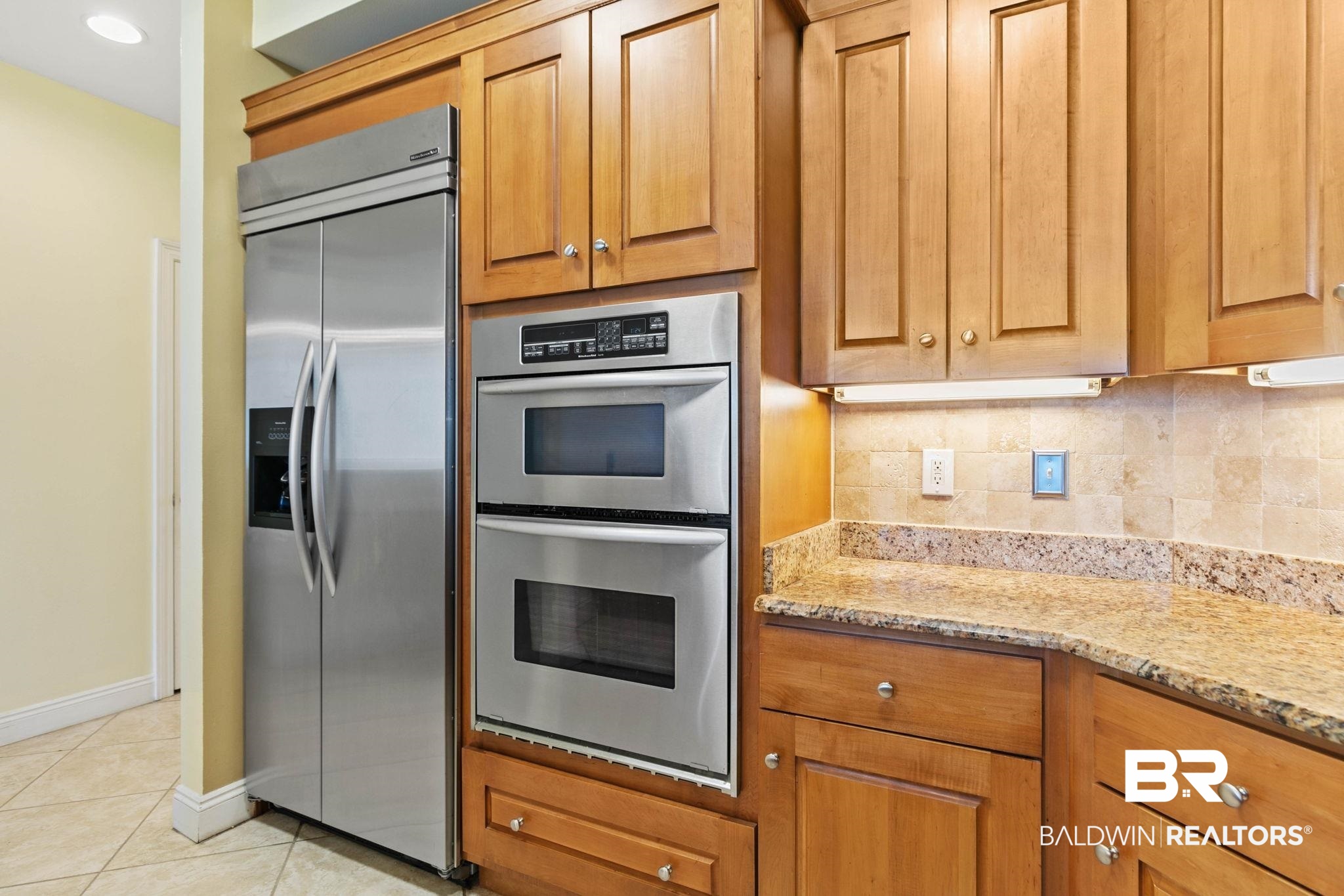 28250 Canal Road, Unit 208 Orange Beach, AL 36561 - Photo 20 of 53 Kitchen featuring stainless steel appliances, light stone counters, wood finish cabinetry, decorative backsplash, and light tile patterned floors