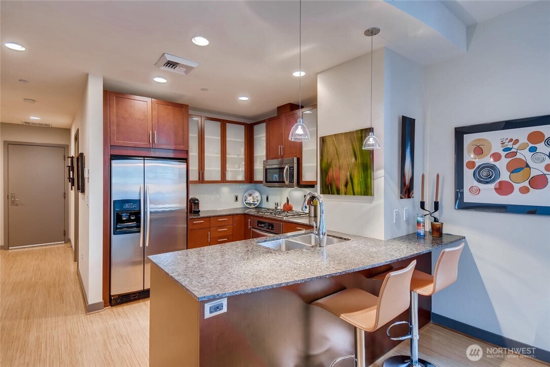 2033 2nd Avenue, Unit 1608 Seattle, WA 98121 - Photo 7 of 33 a kitchen with stainless steel appliances granite countertop a sink refrigerator and cabinets