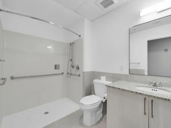 a bathroom with a granite countertop sink a toilet and shower