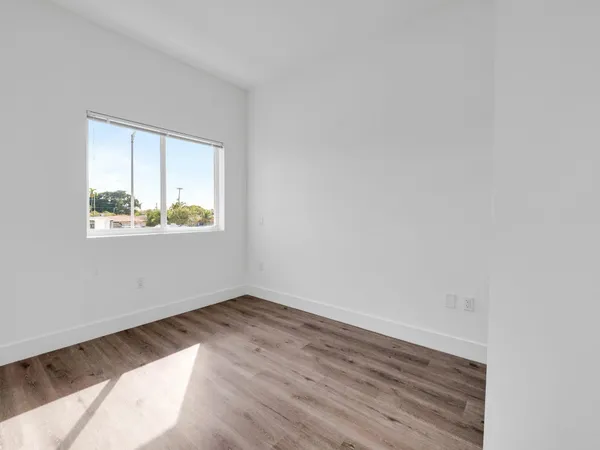 an empty room with wooden floor and window