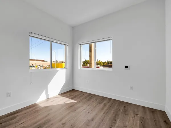 an empty room with wooden floor and windows