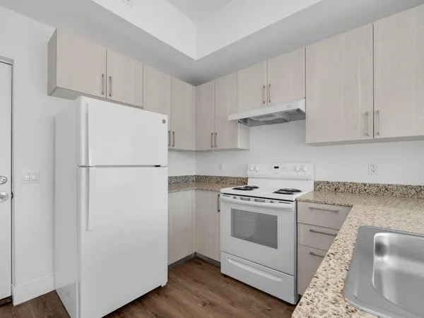 a kitchen with cabinets stainless steel appliances and wooden floor