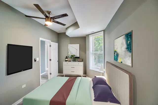 a bedroom with a bed and a flat tv screen on dresser