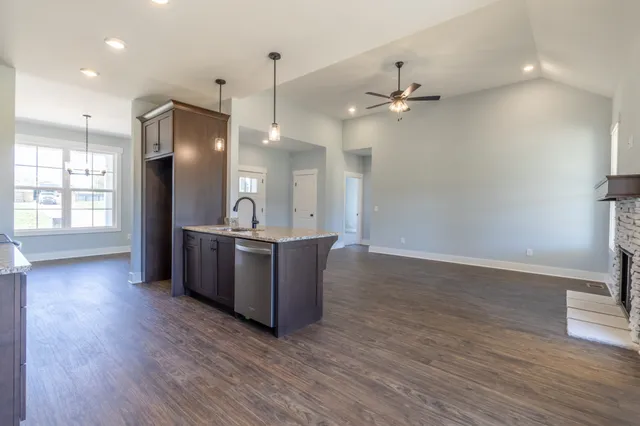 a large kitchen with stainless steel appliances granite countertop a stove and a wooden floors