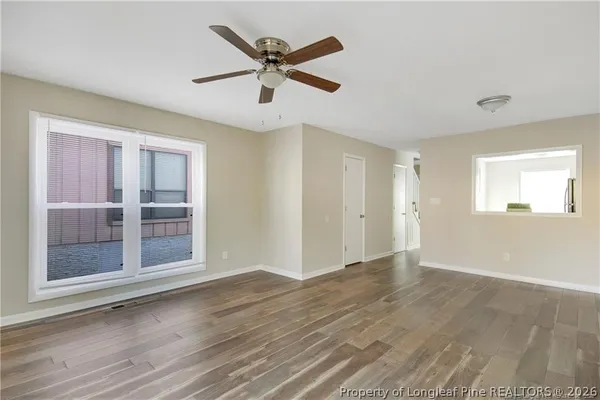 a view of an empty room with wooden floor and a window
