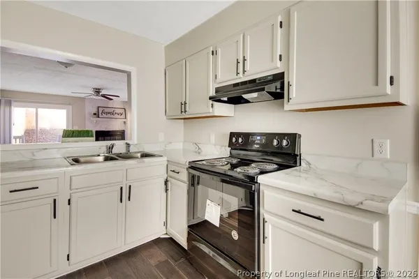 a kitchen with granite countertop white cabinets and white appliances