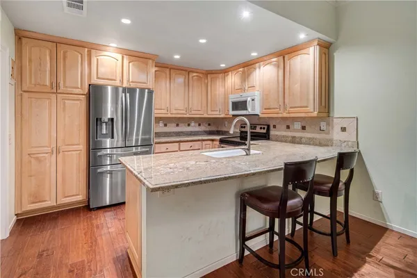 a kitchen with stainless steel appliances granite countertop a table chairs sink refrigerator and cabinets