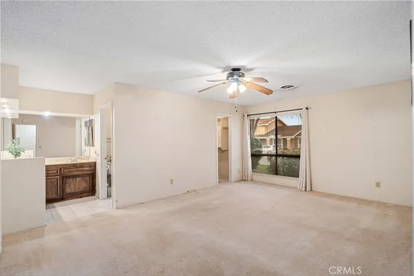 an empty room with chandelier fan and windows